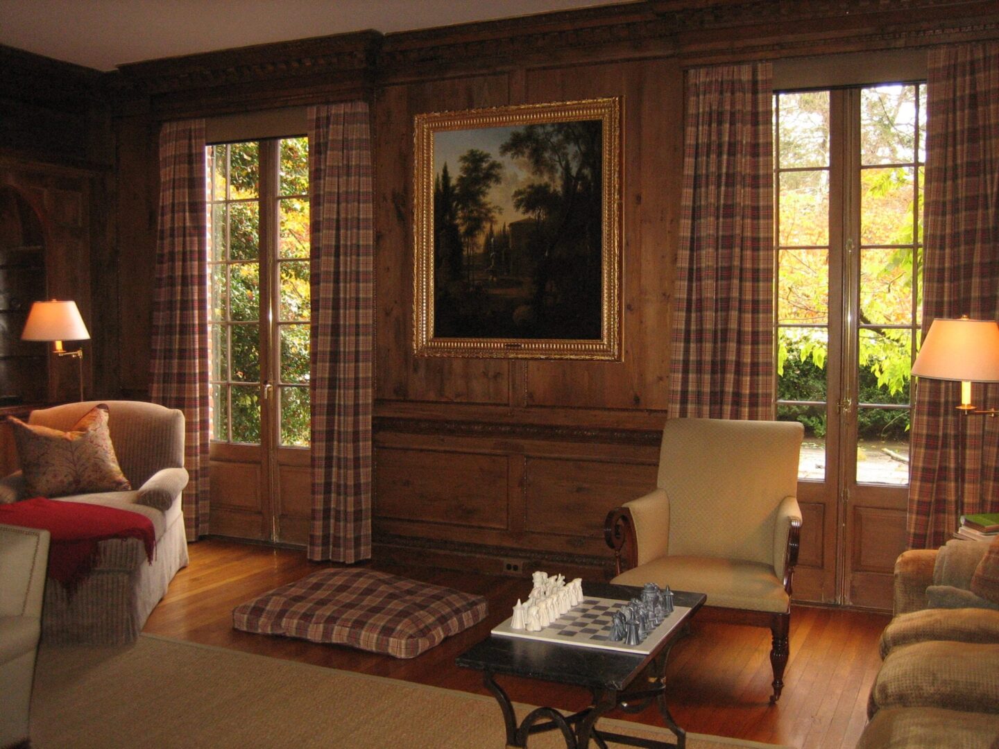 A living room with wood paneling and plaid curtains.