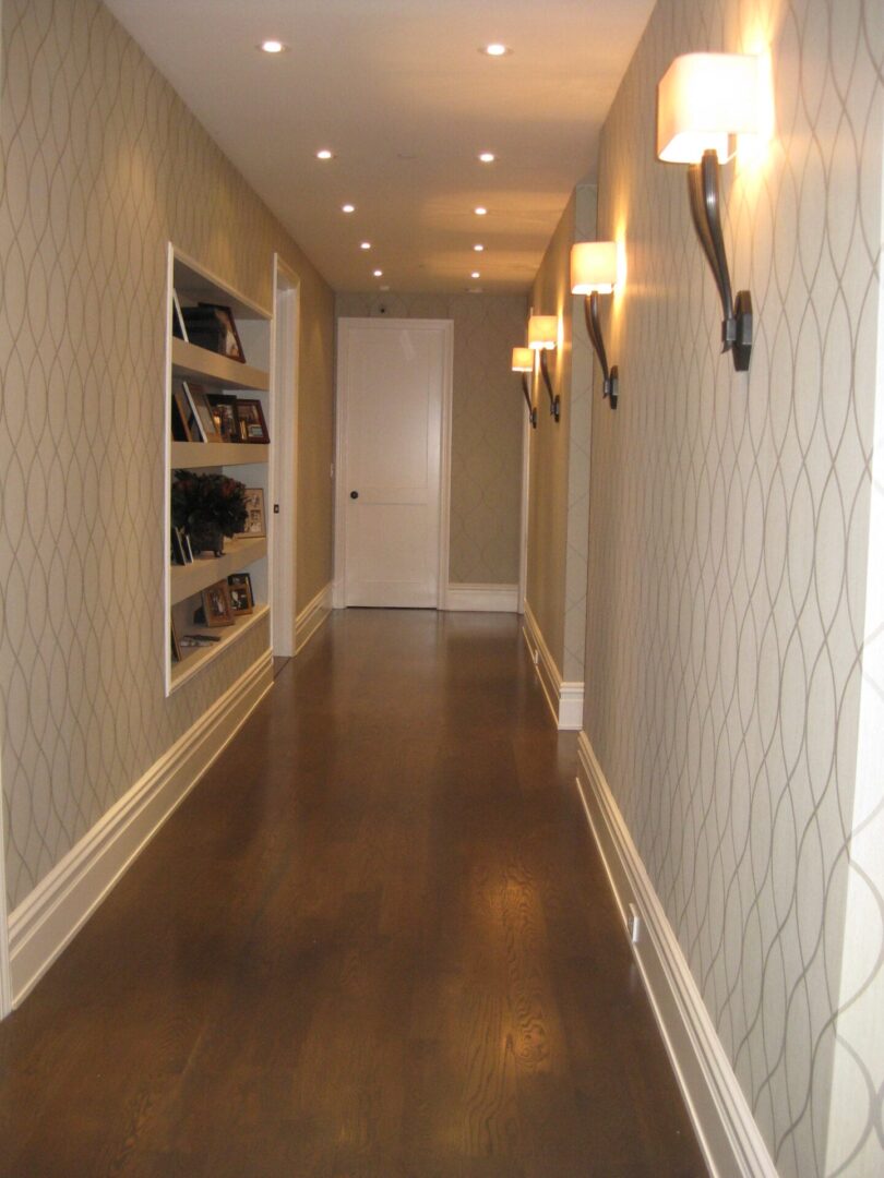 A hallway with shelves and lights on the wall.