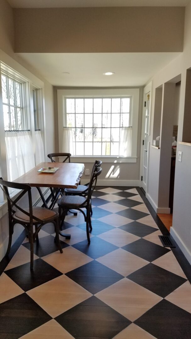 A dining room table and chairs in the middle of a checkered floor.
