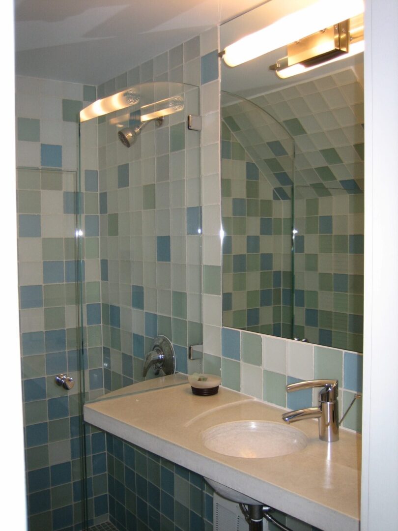 A bathroom with a sink, mirror and tiled walls.
