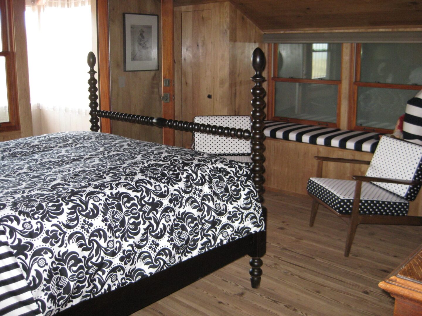 A bedroom with black and white bedding, wooden walls.