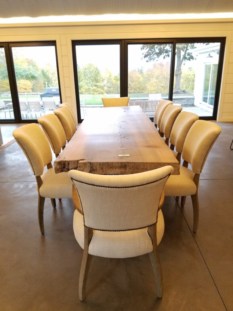 A large table with ten chairs in front of windows.